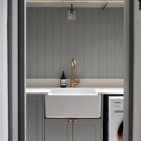White butler sink next to a washer in a laundry room.