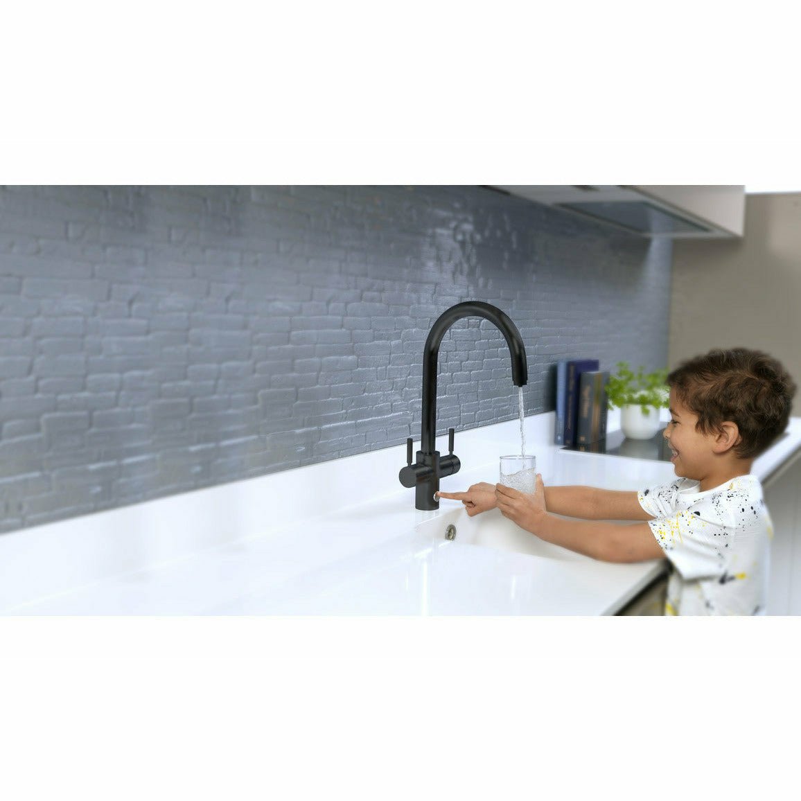 Child uses InSinkErator 4N1 filter water tap to fill a glass with water.